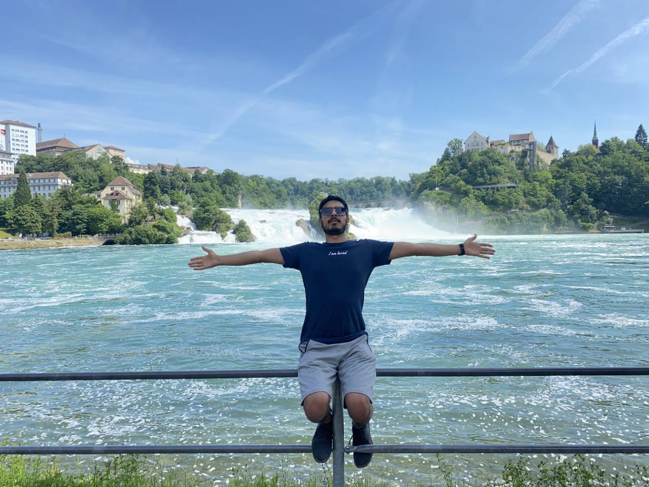 Owais with arms outstretched beside a river and waterfalls
